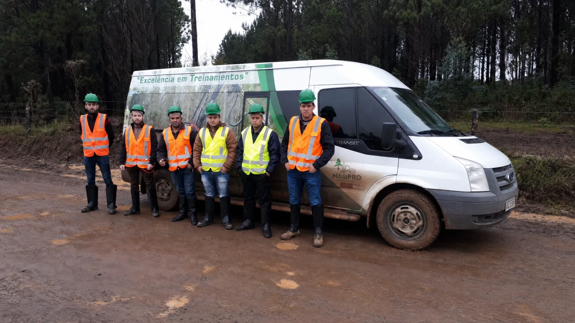 Turma de alunos da MaqPro com EPIs ao lado da van de transporte em área florestal