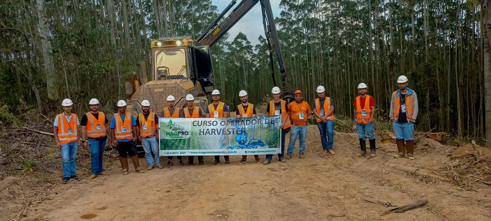 Turma do Curso Operador de Harvester reunida em campo com a máquina ao fundo