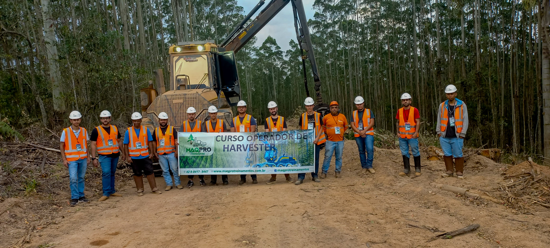Turma do Curso Operador de Harvester reunida em campo com a máquina ao fundo